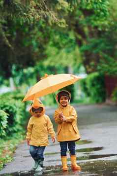 孩子们伞黄色的防水斗篷靴子玩在户外雨
