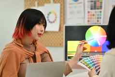 时尚的女设计师解释启动的想法的同事指出桌面电脑颜色斯沃琪样品
