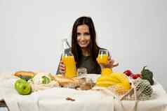 女人绿色t恤倒汁玻璃瓶玻璃表格网生态袋健康的素食主义者蔬菜水果面包零食浪费概念