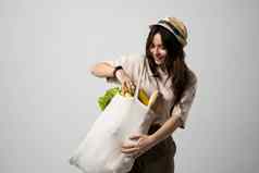 微笑女人t恤他持有可重用的棉花购物袋蔬菜面包绿色概念塑料浪费塑料免费的可持续发展的生活方式
