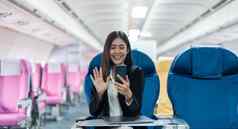 亚洲女移动电话会说话的视频调用飞机业务旅行技术概念