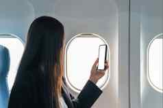 女旅行者乘客坐在窗口座位经济类智能手机持有移动电话白色屏幕模型特写镜头图像