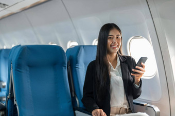 女旅行者乘客坐在窗口座位<strong>经济类</strong>智能手机