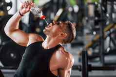 采取打破喝水年轻的运动型强大的男人。黑色的穿锻炼一天健身房