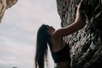 体育女人攀爬岩石年轻的女人苗条的适合身体攀爬火山玄武岩洞穴美丽的海视图运动员女孩火车自然女人克服了困难攀爬路线