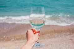 女人手白色酒玻璃绿松石地中海海泡沫波海滩背景