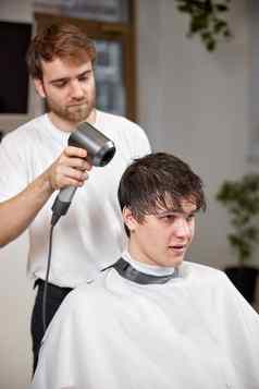 专业理发师工作男人。客户端头发干燥机