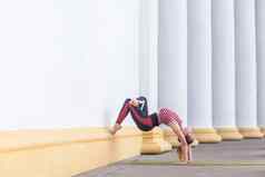 运动美丽的女人穿运动服装wall-assisted倒立构成练习瑜伽