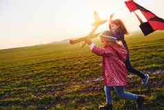 女孩朋友有趣的风筝玩具飞机场阳光明媚的白天