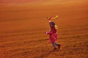 照<strong>亮橙色</strong>彩色的阳光可爱的女孩有趣的玩具飞机美丽的场白天