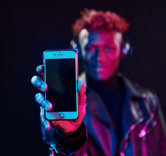 电话耳机未来主义的霓虹灯照<strong>明年</strong>轻的非洲美国男人。工作室