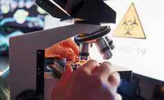 关闭视图男人的手作品显微镜实验室概念冠状病毒