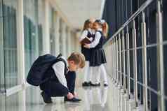 男孩坐着地板上学校孩子们统一的走廊