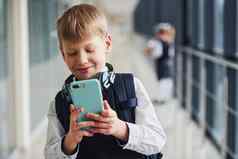 男孩与电话耳机站前面学校孩子们统一的走廊概念教育