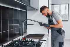 年轻的专业水管工灰色统一的修复水利用厨房