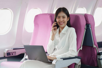 美丽的亚洲业务女人会说话的客户端移动电话飞行工作旅行业务概念