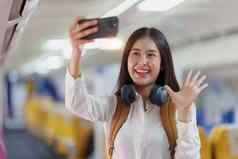 美丽的亚洲旅行者女人自拍照片移动电话飞行飞机工作旅行业务概念