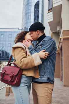 快乐的夫妇休闲温暖的衣服接吻在户外城市业务建筑