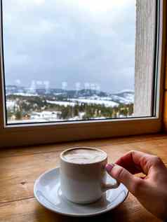 女人持有杯子热咖啡手咖啡馆窗口冬天雪山温暖的白色杯背景冬天森林景观休息放松