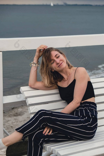年轻的女人坐着板凳上木码头模糊海滨背景有吸引力的女享受海海岸旅行活跃的生活方式概念春天健康幸福精神健康和平慢生活