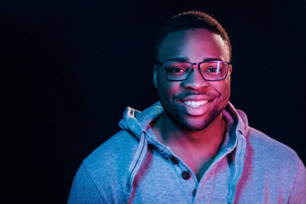 真诚的微笑未来主义的霓虹灯照明年轻的非洲美国男人。工作室