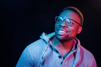 真诚的微笑未来主义的霓虹灯照明年轻的非洲美国男人。工作室