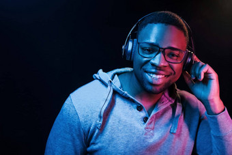 耳机未来主义的霓虹灯照明年轻的非洲美国男人。工作室