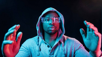 特殊的眼镜未来主义的霓虹灯照明年轻的非洲美国男人。工作室