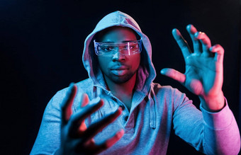 特殊的眼镜未来主义的霓虹灯照明年轻的非洲美国男人。工作室
