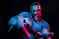 戏剧游戏控制器未来主义的霓虹灯照明年轻的非洲美国男人。工作室