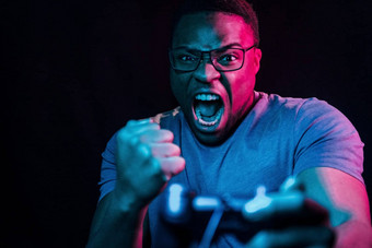 戏剧游戏控制器未来主义的霓虹灯照<strong>明年</strong>轻的非洲美国男人。工作室