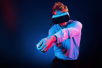 虚拟眼镜游戏经验霓虹灯照明年轻的欧洲男人。黑暗工作室