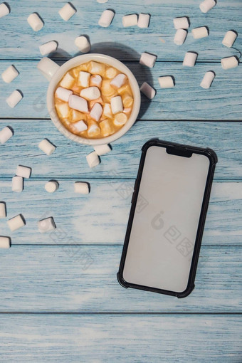 关闭杯热巧克力棉花糖可可舒适的咖啡棉花糖移动电话白色屏幕复制空间模拟品牌木蓝色的背景复制空间文本壁纸设计