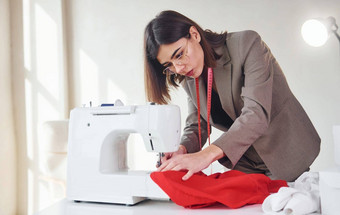 裁缝作<strong>品红</strong>色的布年轻的女人正式的衣服在室内概念风格