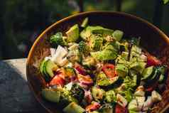 鳄梨混合蔬菜沙拉白天在户外新鲜的沙拉西红柿鳄梨生菜洋葱黄瓜健康的排毒食物概念生酮饮食