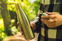 特写镜头认不出来女手持有水瓶可重用的钢热水瓶公园可持续发展的生活方式塑料免费的浪费免费的生活绿色女人喝水公园