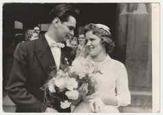 古董照片显示新婚夫妇前面教堂新娘持有群花白色康乃馨复古的黑色的白色摄影约