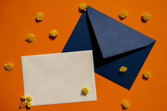 美丽的黄色的洋甘菊雏菊花邮政蓝色的信封橙色背景空纸请注意复制空间文本春天时间问候卡假期极简主义概念生动的颜色有创意的