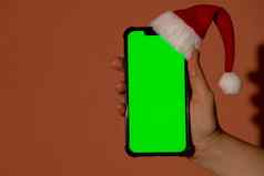 移动电话穿着圣诞老人的红白他浓度关键屏幕红色的背景概念圣诞节年假期女手持有空白细胞电话数字小工具无线愿望列表概念社会媒体广告