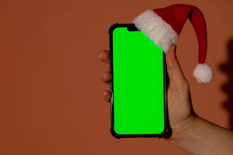 移动电话穿着圣诞<strong>老人</strong>的红白他浓度关键屏幕红色的背景概念圣诞节年假期女手持有空白细胞电话数字小工具无线愿望列表概念社会媒体<strong>广告</strong>