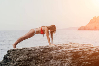 女人海瑜伽回来视图免费的平静幸福满意女人长头发站前岩石瑜伽位置天空海健康的生活方式在户外自然健身概念