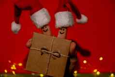 手指穿着圣诞老人的红白帽子快乐手指表情符号脸持有纸礼物盒子现在红色的背景快乐家庭庆祝概念圣诞节年一天夫妇
