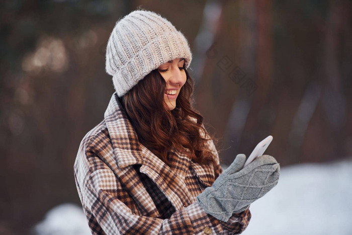 电话美丽的女人温暖的衣服走冬天森林