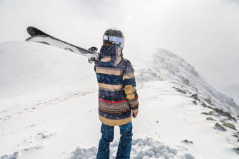 滑雪站前山享受视图美丽的冬天山多云的一天女人滑雪西装持有滑雪板肩膀