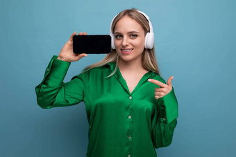 水平照片时尚的欧洲女人显示智能手机屏幕摩卡普蓝色的工作室背景免费的空间
