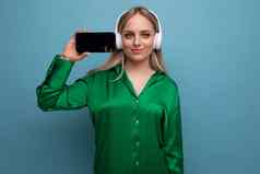 水平照片时尚的欧洲女人持有智能手机屏幕面对向前蓝色的工作室背景免费的空间