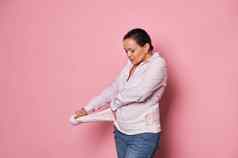 怀孕了女人把支持绷带减少背痛孤立的粉红色的整形腹部支持带概念