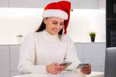 快乐女人红色的圣诞老人老人他信贷卡智能手机在线购物