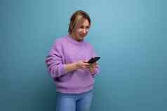 金发碧眼的女人紫色的连帽衫聊天智能手机蓝色的背景