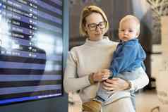 妈妈。旅行孩子持有婴儿婴儿男孩机场终端检查飞行时间表等待董事会飞机旅行孩子们概念